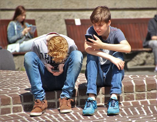 2 boys sitting on the floor looking at their phone