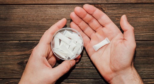 hands holding a tin with nicotine pouches